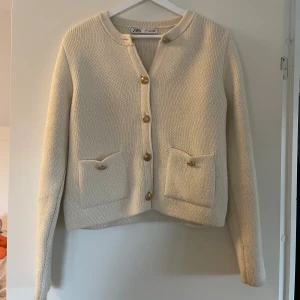 Vit stickad kofta från Zara - Superfin vit stickad kofta från Zara med guldiga knappar och två fickor framtill. Väldigt liten i storleken därför är den L men brukar vanligtvis ha S