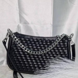 Michael kors axelväska med kedja  - Snygg svart Michael kors väska med flätad design och en grov silverfärgad kedja som detalj. Väskan har dragkedja upptill och en smidig axelrem. Perfekt storlek för det viktigaste och ger en cool vibe till din outfit. Helt ny med lappar kvar 