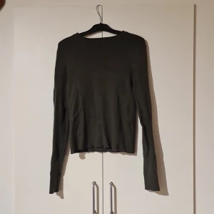 Mörkgrön ribbad stickad tröja - En mörkgrön, ribbad stickad tröja med rund hals och långa ärmar. Tröjan har en enkel och clean design som är lätt att matcha med olika outfits. Perfekt för lager-på-lager under kyligare dagar. Kolla in mina andra saker jag säljer:)