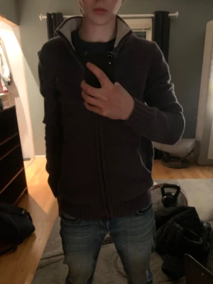 Mörkblå stickad kofta från Henry Choice - Säljer en mörkblå stickad kofta från Henry Choice i storlek L men kan passa för folk i M med. Koftan har dragkedja framtill, ribbade muddar och krage med vit insida. Två fickor på framsidan och snygg, enkel design som funkar till jeans.