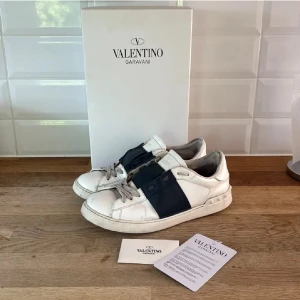 Valentino Garavani Open sneakers  - Säljer ett par Valentino Garavani Open sneakers i vit skinn, perfekt skick, negativa är lite slitna på insidan men inget som märks vid användning eller känns av. Allt på bild ingår vid köp. Köpta av Trendsellers så ÄKTA. Perfekta skorna för dig !