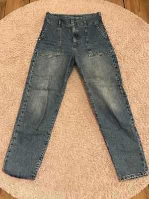 Blå high waist jeans från g perfect jeans - Säljer ett par blå high waist jeans från g perfect jeans i storlek 38. Jeansen har raka ben, stora fickor fram och klassiska bakfickor. Materialet är slitstarkt denim och färgen är snyggt tvättad blå. Perfekta till sneakers eller boots.