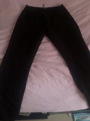 Svarta kostymbyxor från BikBok - Snygga svarta kostymbyxor från BikBok i storlek 36. Byxorna har en klassisk rak passform och är perfekta för en stilren look. Materialet känns mjukt och följsamt, och midjan är normal. Passar dig som gillar enkel och clean stil. Säljer de pågrund av att det inte passar mig längre 