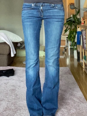 G-Star RAW Midge Bootcut jeans blå - Säljer ett par G-Star RAW Midge Bootcut jeans i klassisk blå färg. Modellen har bootcut-snitt med lätt utsvängda ben och snygga detaljer på bakfickorna. Jeansen är tillverkade i slitstarkt denim och har normal passform med låg midja. Storlek W28 L34 innerbenslängd 84 cm midjemått 38 cm