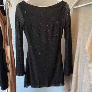 Glittrig klänning med öppen ryg - Klänningen har vida ärmar och är på mig (som är 158cm) i höftlängd, oanvänd 