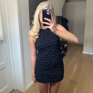Svart strukturerad kortklänning - Supersnygg svart kortklänning med strukturerat tyg och hög hals. Ärmlös modell som sitter tight och markerar figuren. Från märket COS med nypris 900kr men jag säljer för 400kr då den endast är använd 1-2 gånger☺️därav inga defekter! (Obs jag har vikt upp den lite)