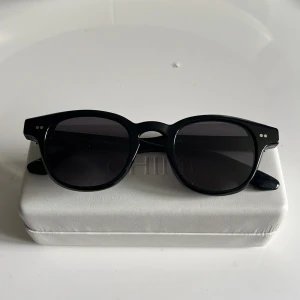 Svarta solglasögon CHIMI Core 01 - Snygga svarta solglasögon från CHIMI, modell Core 01. De har en klassisk rundad form med tjock båge och mörka glas. Passar perfekt för dig som vill ha en stilren look. De är använda endast ett fåtal gånger så man ser inga tecken på användning.