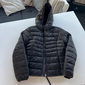 Svart jacka - Säljer en svart pufferjacka med huva och dragkedja. Jackan har quiltad design och är vadderad för extra värme. Perfekt för kyliga dagar och har en modern, lite oversized passform. Står ingen storlek men passar xs-s. Kolla gärna in mina andra annonser, jag ger paketpris!!