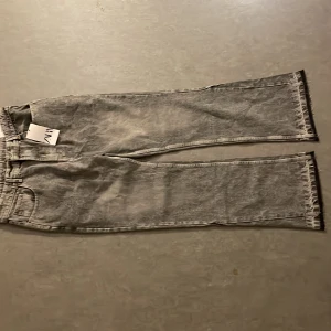Grå straight jeans från Zara, M - Grå tvättade straight fit jeans från Zara i storlek M. Klassisk femficksmodell med bälteshällor och raka ben. Jeansen har en cool, lite sliten look och är tillverkade i denim. Perfekta för dig som gillar en avslappnad men stilren vibe.