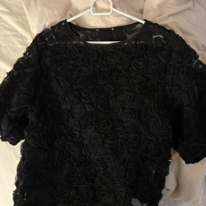 Svart blus - Säljer denna snygga svarta blus med blom detaljer, blusen är genomskinlig och knappt använd💘