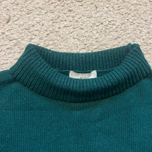 Mörkgrön stickad tröja - Mysig mörkgrön polotröja från H&M med ribbad hög krage och breda muddar vid ärmslut och nederkant. Knappt använd men köpt från sellpy. Säljer pga den inte kommer till användning. Skriv vid frågor!