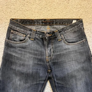 Mörkgrå jeans från Nudie Jeans - Snygga mörkgrå jeans från Nudie Jeans med raka ben. Säljer pga dom är för små för mig. Knappt använda men köpta från sellpy. Skriv för fler bilder!