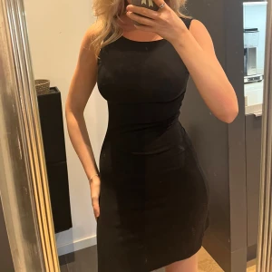 Svart tight klänning Gina Tricot XS - En svart, tight och ärmlös klänning från Gina Tricot i storlek XS. Klänningen har en klassisk rund halsringning och kort längd som sitter snyggt figurnära. Perfekt för dig som gillar en enkel men stilren look.