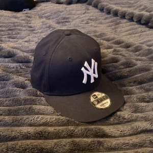 Svart New Era Yankees keps S/M - Säljer en svart New Era 9FIFTY snapback keps med klassiskt New York Yankees broderat vitt logotyp framtill. Kepsen är tillverkad i 100% bomull och har justerbar snapback baktill för perfekt passform. Kepsen är knappast använd