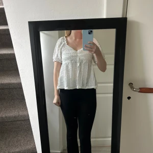 Vit blus med volang och v-ringning - Säljer en söt vit blus med v-ringning och korta puffärmar. Blusen har volangdetaljer och ett smockat, strukturerat tyg som ger en luftig känsla. Den kan bäras både på axlarna och offshoulder för en trendig look. Perfekt till jeans eller kjol. Strl: S, passar även M🩷