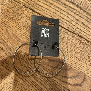 Silvriga örhängen  - Säljer ett par örhängen i silverfärg köpta från Åhléns. De är aldrig använda. 