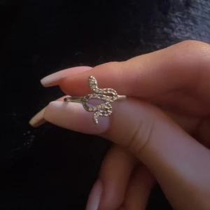 Silvrig ormring i äkta silver - Cool ring i äkta silver 925 med en ormformad design och små glittrande stenar på ovansidan. Perfekt statement-piece för dig som gillar unika smycken med edge.
