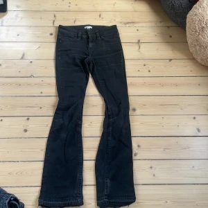 Svarta bootcut jeans från Gina Tricot - Svarta jeans från Gina Tricot i storlek 164. Modellen har bootcut-ben och klassisk femficksdesign. Jeansen är tillverkade i ett stretchigt bomullsmaterial och har snygga slitningar för en cool look.