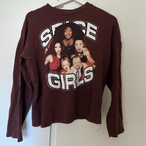 Brun Vintage Spice Girls långärmad tröja - Brun långärmad tröja med stort Spice Girls-tryck på framsidan. Tröjan är i 100% polyester. Tröjan har en lös söm i halsringen som behöver lagas (se bild) därav lågt pris! Kan mötas upp på Södermalm!
