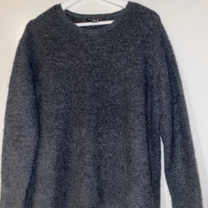 Mörkgrå stickad tröja från Amisu - Mysig mörkgrå stickad tröja från Amisu med rund halsringning och lång ärm. Perfekt för lager-på-lager och chill dagar. Enkel och stilren design som funkar till det mesta. Säljes i storlek S.
