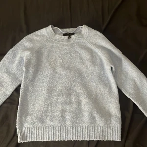 Ljusblå stickad tröja från Vero Moda - Supermysig ljusblå stickad tröja från Vero Moda. Tröjan har en klassisk rund halsringning, ribbade muddar och är långärmad. Perfekt för lager-på-lager och chill dagar. Enkel och stilren design som passar till det mesta. Tröjan har en liten fläck som du kan se på sista bilden, den syns bara i vissa ljus.