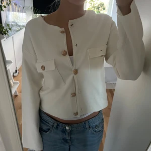 Vit kofta med guldknappar  - Superfin vit kofta från H&M med snygga guldknappar och två fickor framtill. Koftan är helt oanvänd! Skriv vid frågor😊