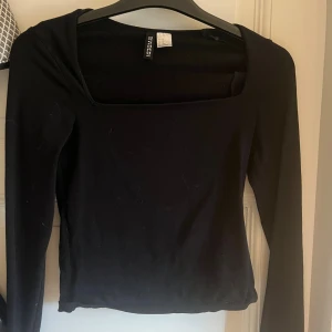 Svart långärmad topp från H&M Divided - En svart långärmad topp från H&M Divided med fyrkantig urringning. Toppen är i en slim passform och tillverkad i mjuk bomull, perfekt att styla med jeans eller kjol. Enkel och stilren design som funkar till många olika looks.
