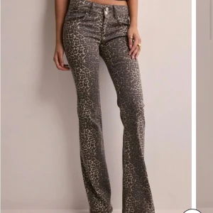 Leopardmönstrade bootcut jeans från Nelly - Snygga bootcut jeans från Nelly med leopardmönster i mörkbruna och beige toner. Byxorna har låg midja. Materialet är jeans med stretch för en bekväm passform. Perfekta för dig som vill sticka ut med ett djurmönstrat statement.