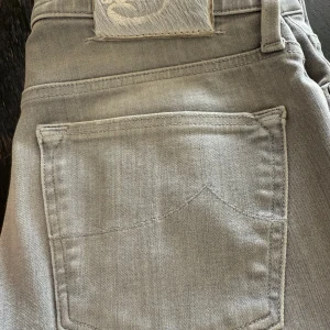 Grå skinny jeans från Jacob Cohën - Snygga grå jeans från Jacob Cohën i skinny fit. Byxorna har klassisk femficksdesign, silverfärgad knapp med J-logga och exklusiva detaljer på insidan. Materialmix med bomull och stretch för en mjuk känsla och bra passform. Stl 27. 