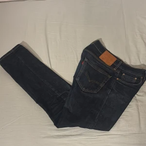 Levi's 502 mörkblå jeans - Säljer ett par Levi's 502 jeans i mörkblå tvätt med klassiska fem fickor och snygga kontrastsömmar. Jeansen har en taper passform och är tillverkade i slitstarkt denim. Perfekta för dig som gillar en tidlös och clean look. Tar emot frågor o bud!