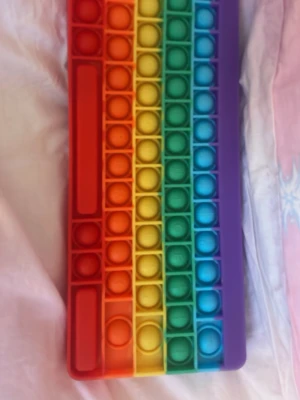 Pop it  - Bilderna visar en pop it-leksak i regnbågens färger formad som ett tangentbord.