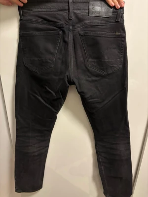 Svarta G-Star RAW 3301 jeans, W29 L32 - Säljer ett par svarta G-Star RAW 3301 jeans med straight tapered passform. Klassisk femficksmodell med snyggt tvättad finish och diskret logga bak i midjan. Jeansen är tillverkade i ett mjukt och slitstarkt bomullsmaterial.