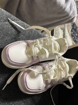 Vita och ljuslila sneakers med gummisula - Säljer ett par snygga sneakers i vitt och ljuslila med klassisk snörning och grov gummisula. Skorna är från soc med storleken 32 och de är nästan oanvända. 