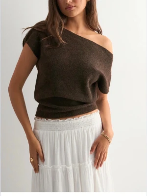 Brun offshoulder topp från Nelly - Mysig brun offshoulder topp från Nelly i stickat material. Toppen har en lös passform och är ärmlös, perfekt att styla med kjol eller jeans. Enkel och stilren design som ger en avslappnad men trendig look. Använd ett fåtal gånger🩷