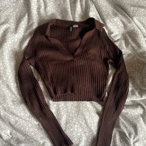Brun topp - En brun ribbad långärmad topp med krag detaljer. Tröjan är kort och i ett mjukt material!