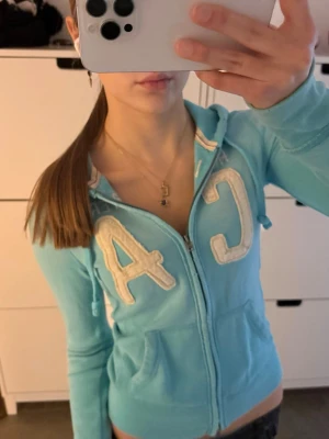 Unik vintage turkos/ljusblå Hollister zip up hoodie - Vintage Hollister huvtröja med dragkedja i en unik turkos/ljusblå färg! Storlek XS! I bra skick, förutom en defekt på armen, men jag har bara tvättat den normalt, den borde gå bort med ett starkare tvättmedel! Har den vita logotypen över bröstet.