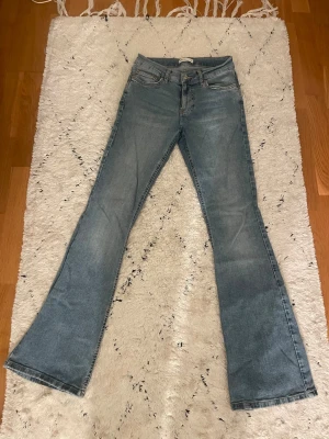 Bootcut ljusblå jeansbyxor - Säljer ett par ljusblå bootcut jeans i storlek 36, jeans har ett litet lagat hål bak på jeansen därav priset.