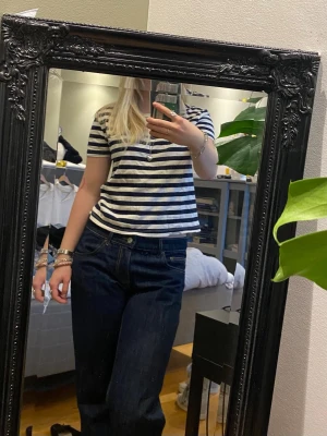 Randig blåvit t-shirt - Säljer en klassisk blåvit randig t-shirt med korta ärmar och rund hals. T-shirten har en avslappnad passform och är gjord i mjuk bomull, perfekt till jeans eller shorts. Enkel och tidlös design som alltid funkar.