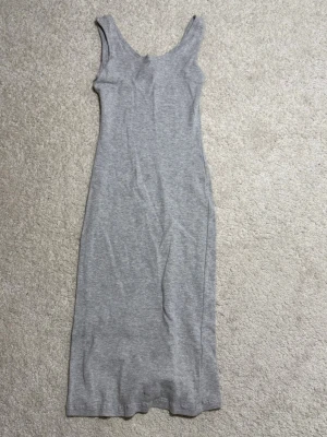 Grå långklänning från Primark - En enkel och stilren grå långklänning från Primark. Klänningen är ärmlös med rundad halsringning och har en rak passform. Perfekt för en avslappnad look.