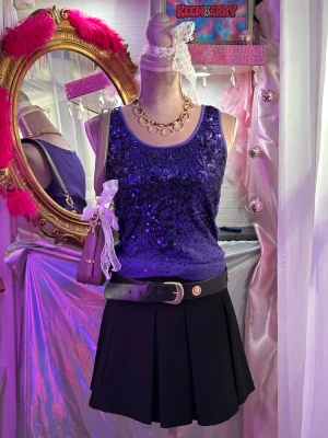 Lila paljettlinne med breda axelband - Säljer ett lila linne med breda axelband, täckt av glittriga paljetter framtill. Toppen har en rund halsringning och är figurnära i passformen. Perfekt för dig som vill sticka ut och glänsa lite extra.