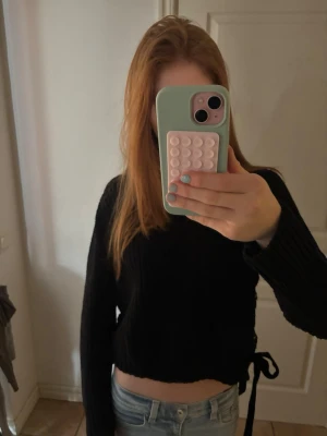 Svart stickad tröja med snörning - ‼️PRIS KAN DISKUTERAS‼️ Säljer en svart croppad stickad tröja med långa ärmar och snygg snörning i sidorna. Tröjan har en ribbad struktur. Perfekt till jeans eller kjol för en trendig look. Passar mig som använder S, så skulle säga att det är en mer S i storleken än M. 
