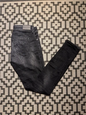 Svarta Replay jeans (prisförslag! - Märke: Replay Storlek: 27/30 Passform: Slim fit Färg/Tvätt: Mörkgrå/svart tvätt med diskret slitning Skick: Mycket fint skick – sparsamt använda, inga hål eller fläckar  Snygga och välsittande Replay-jeans i hög kvalitet. Den smala passformen ger ett modernt intryck och den stilrena mörka tvätten gör dem enkla att matcha till både vardag och fest.