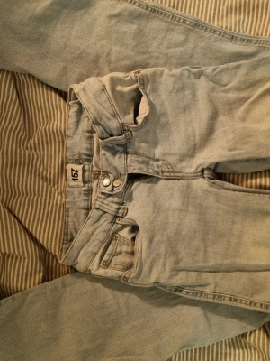 Ljusblå jeans från 157, storlek XS - Ljusblå jeans från 157 i klassisk femficksmodell med raka ben och normal passform. Jeansen har dubbla metallknappar i midjan och är tillverkade i bomullsdenim. Perfekta för dig som gillar en enkel och tidlös look.