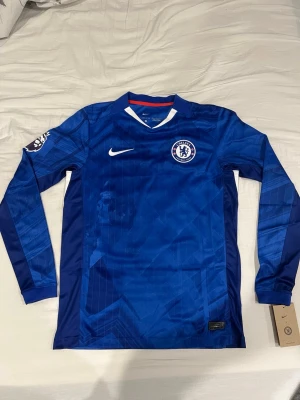 Chelsea långärmad Estevo Tröja - Säljer denna tröja då jag fick fellskick från Chelsea Store. Tröjan är helt äkta och kostade runt 2000kr. Tröjan har PL och No Room for racism vilket kostade runt 600kr extra, tröjan är i storlek S men passar även M. Varför jag säljer är för att shoppen var inte så hjälpsamma med retur så jag får sälja den själv helt enkelt. För fler frågor kontakta mig.