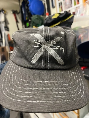 Svart keps Byron Bay brodyr - Säljer en svart keps med vit kontrastsöm och broderad Byron Bay-logga framtill och baktill. Kepsen har justerbar snapback och är tillverkad i bomullstyg. Snygg detalj med ett stort broderat X på framsidan.