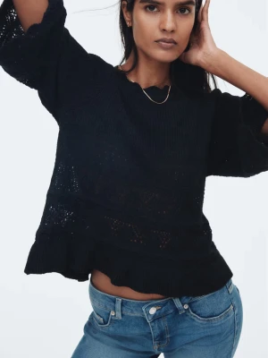 Pointellestickad tröja med volang - Supersnygg svart stickad tröja med vida trekvartsärmar och volangkant nertill. Tröjan har ett fint hålmönster och känns både luftig och mysig. Perfekt att styla med jeans för en chill look. 