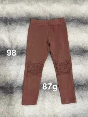 Röd/Bruna leggings med spetsdetaljer - Snygga bruna/röda leggings med dekorativa spetsdetaljer över knäna. Perfekta för dig som vill ha något enkelt men ändå med en twist.🌸 Fint använt skick. Storlek 98 ( brunröd färg )