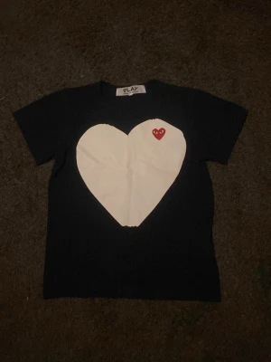 Marinblå Comme des Garçons Play t-shirt - Marinblå t-shirt från Comme des Garçons Play med stort vitt hjärta och det klassiska röda hjärtat med ögon på bröstet. T-shirten har rund hals och korta ärmar. Tillverkad i mjuk bomull för skön känsla och clean look.