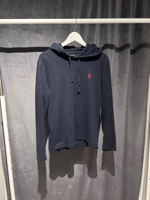Ralph Lauren hoodie - Stil ren Ralph lauren hoodie, mörkblå med rött märke. Hoodien är tunnare än vanliga hoodie vilket är perfekt inför våren och sena sommar kvällar. Hoodien är i storlek Xs men passar också S. Skriv vid mina fundering!