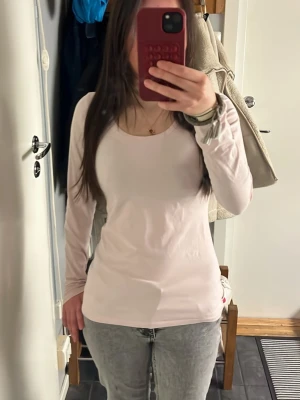 Gina Tricot  - Säljer en enkel och stilren ljusrosa långärmad topp från Gina Tricot. Toppen har rund halsringning och är gjord i mjuk bomull som sitter skönt mot kroppen. 